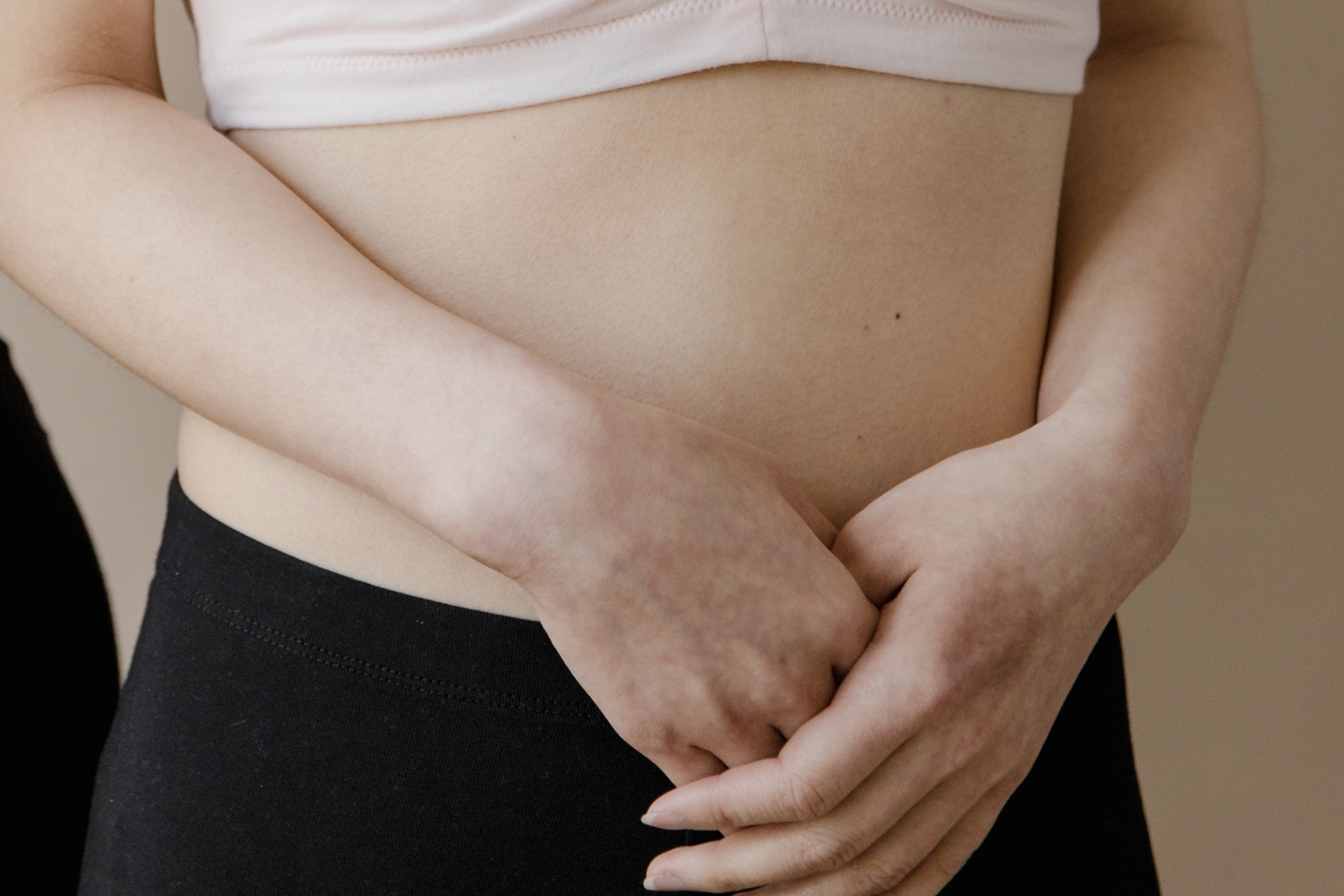 person pressing both hands on to tummy